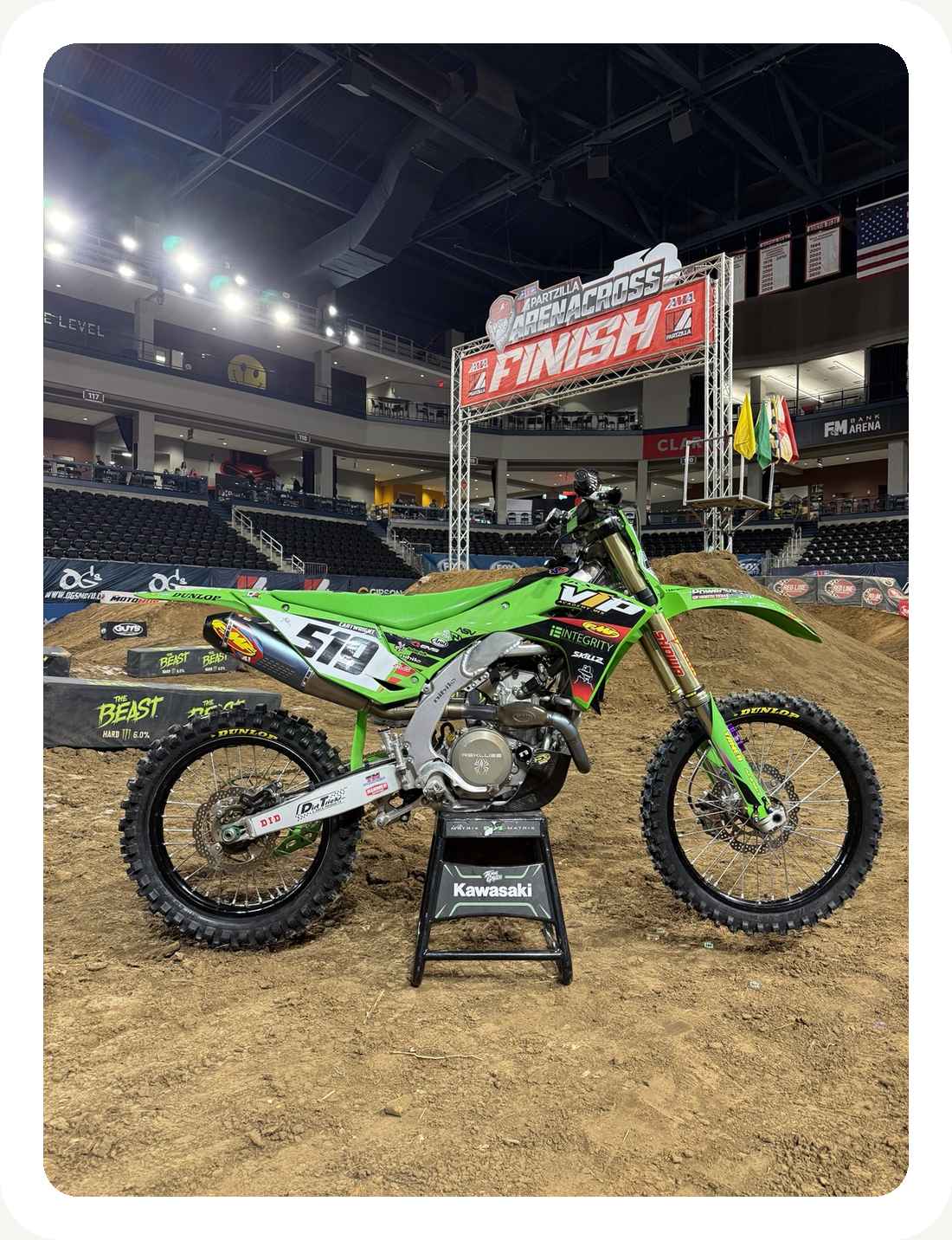 Green Kawasaki motocross race bike parked inside an arena
